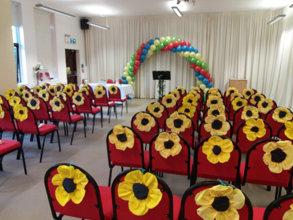 Sunflower decorations on the backs of red chairs set up for a wedding ceremony