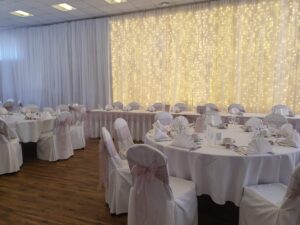 full white draping with partial lighting behind the top table