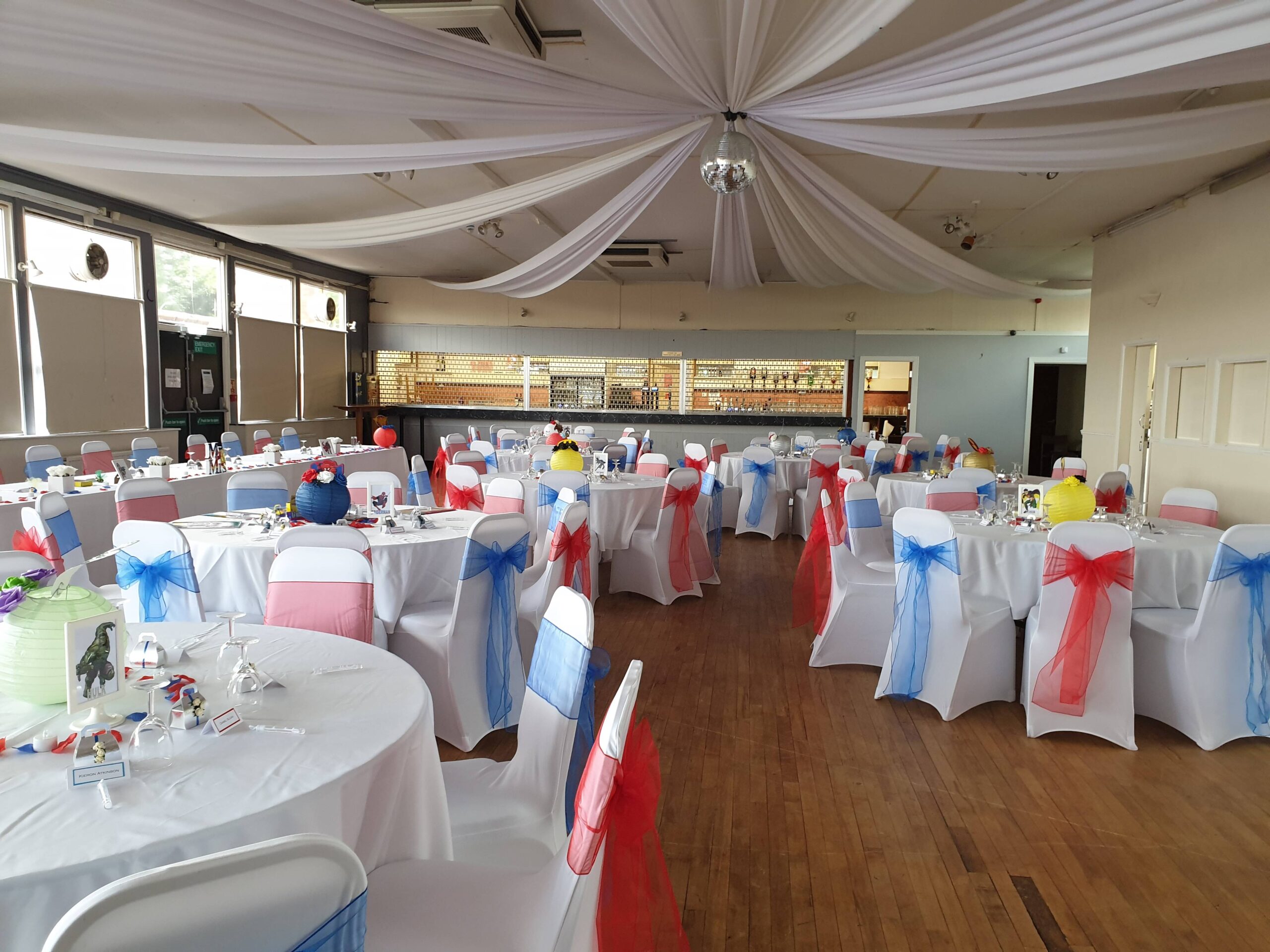 Community hall with red and blue themed chairs and white ceiling drape