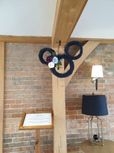 Navy blue Disney logo Mickey Mouse wreath hanging from a wooden beam at a barn venue