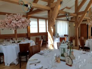 barn venue with rustic beam set up with white clothed tables and lanterns or cherry blossom trees as table centres